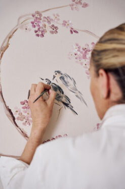 chica rubia pintando un pajaro en un mural